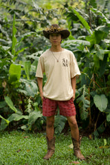 Male wearing ‘Āina Tee and red palaka shorts with cowboy boots